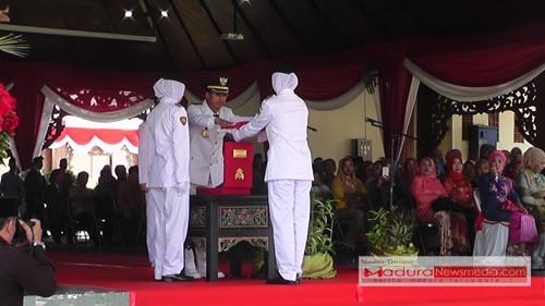 Bupati Pamekasan, Achmad Syafii saat menyerahkan Bendera Merah putih kepada anggota Paskibraka